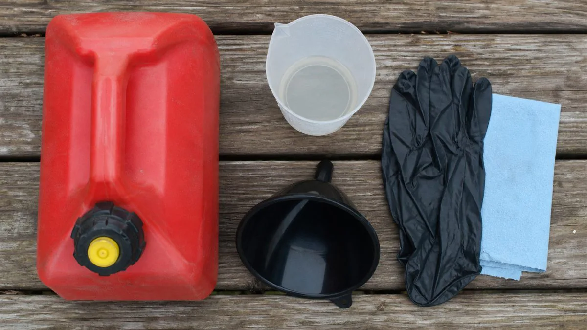 Fuel can, measuring cup, funnel, gloves, and shop towel arranged for mixing two-stroke fuel