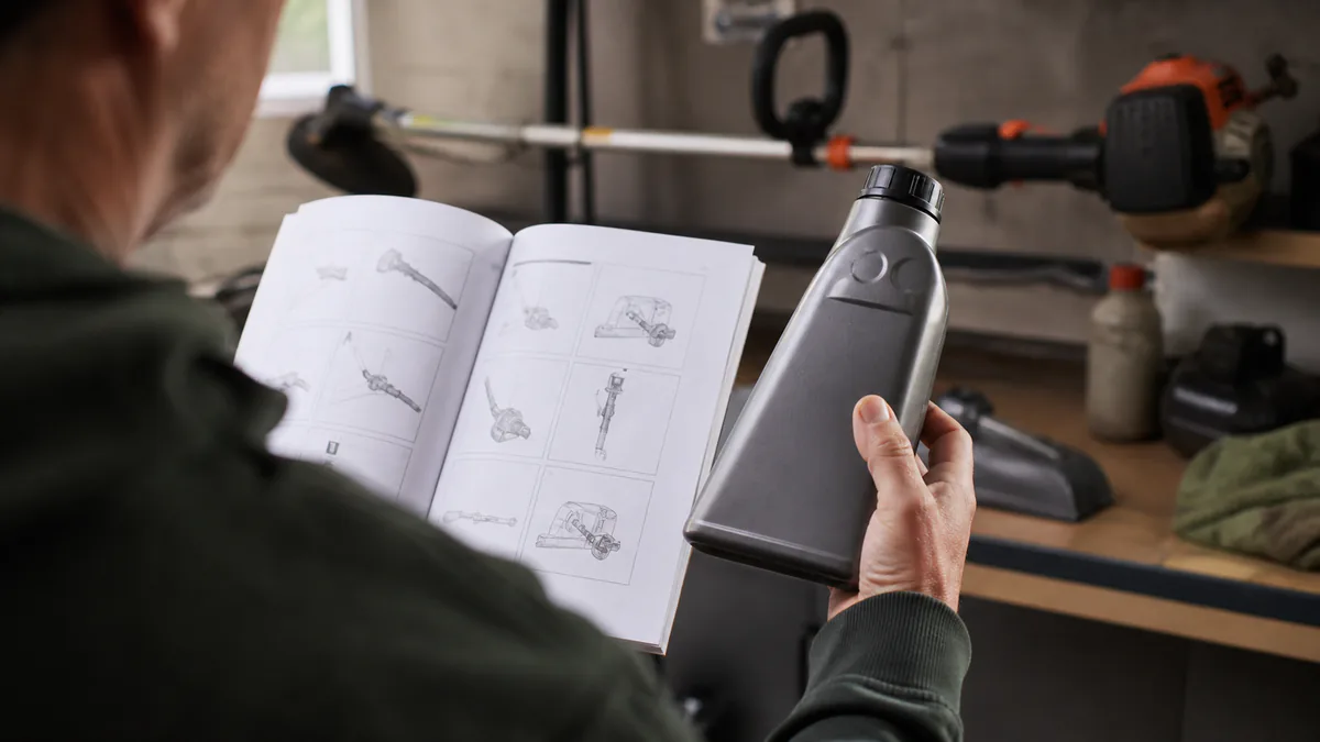 Equipment owner checking a plain two-stroke oil bottle against an open string-trimmer manual
